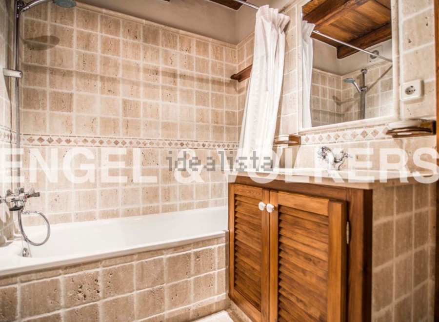 Charming bathroom with beige tile, wooden vanity, and built-in bathtub.