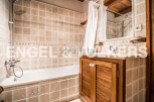 Charming bathroom with beige tile, wooden vanity, and built-in bathtub.