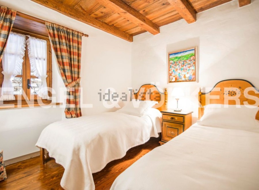 Charming rustic bedroom with twin beds, featuring wooden beams and a cozy atmosphere.