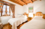 Charming rustic bedroom with twin beds, featuring wooden beams and a cozy atmosphere.