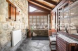 Rustic stone cottage with wooden beams and large windows offering stunning mountain views.