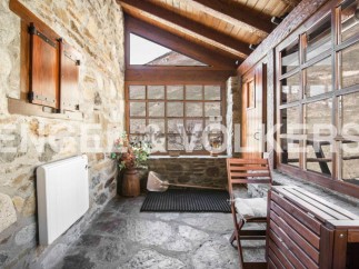 Rustic stone cottage with wooden beams and large windows offering stunning mountain views.