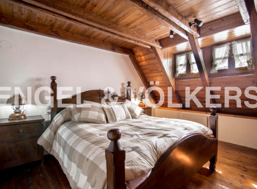 Charming attic bedroom with wooden beams and sloped ceilings.