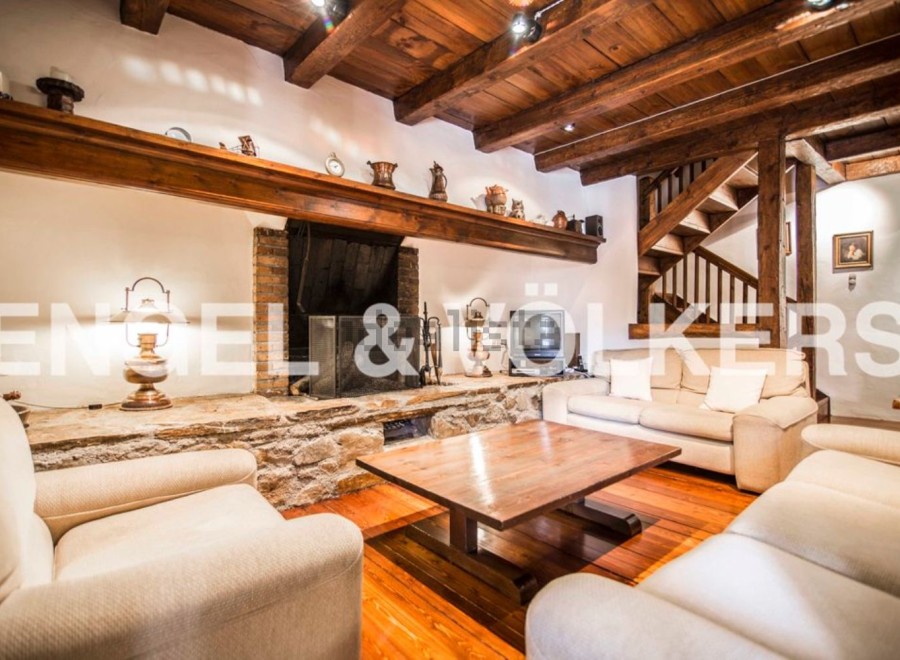 Rustic living room with exposed wooden beams, a stone fireplace, and comfortable sofas.
