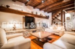 Rustic living room with exposed wooden beams, a stone fireplace, and comfortable sofas.