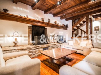 Rustic living room with exposed wooden beams, a stone fireplace, and comfortable sofas.