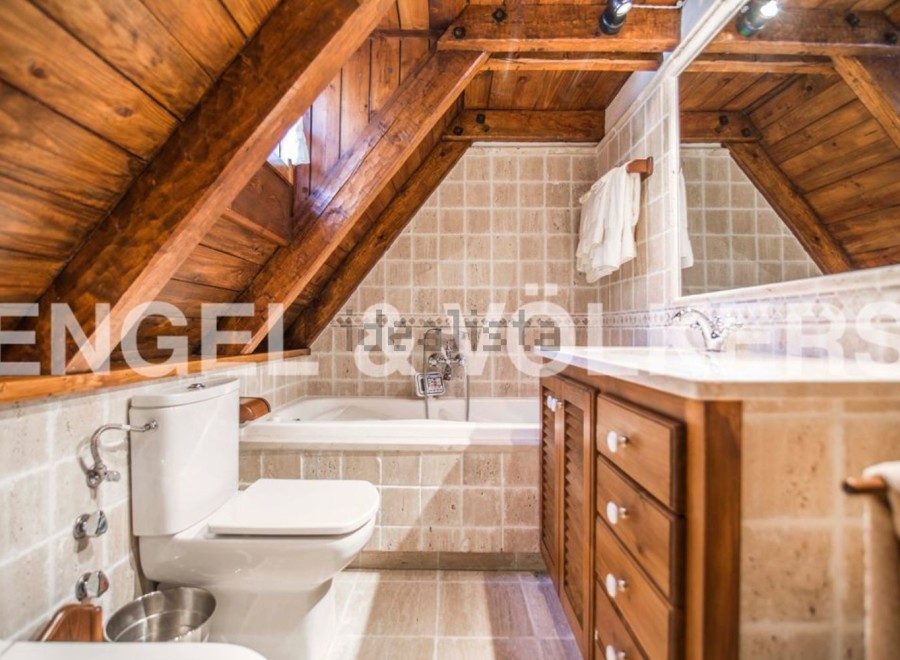 Charming attic bathroom with wooden beams, tiled walls, and a built-in vanity.