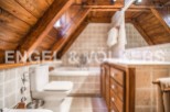 Charming attic bathroom with wooden beams, tiled walls, and a built-in vanity.