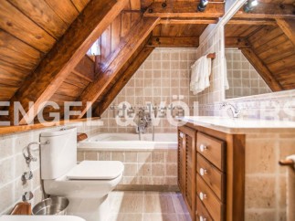 Charming attic bathroom with wooden beams, tiled walls, and a built-in vanity.