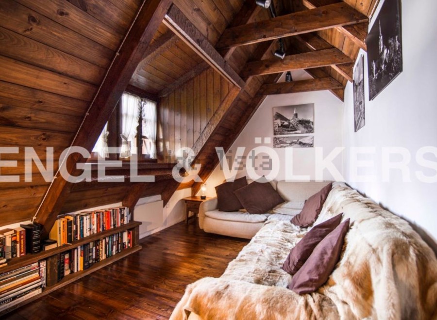 Cozy attic apartment with wood-beamed ceilings and a large, comfortable couch.