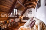 Cozy attic apartment with wood-beamed ceilings and a large, comfortable couch.