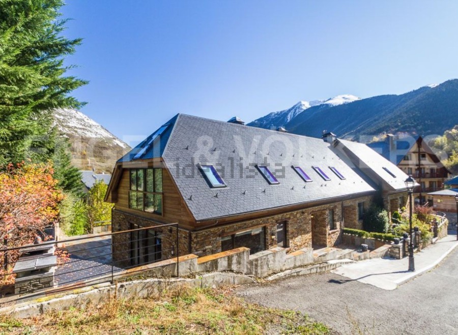Mountain view home with large windows and stone exterior.