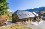 Mountain view home with large windows and stone exterior.