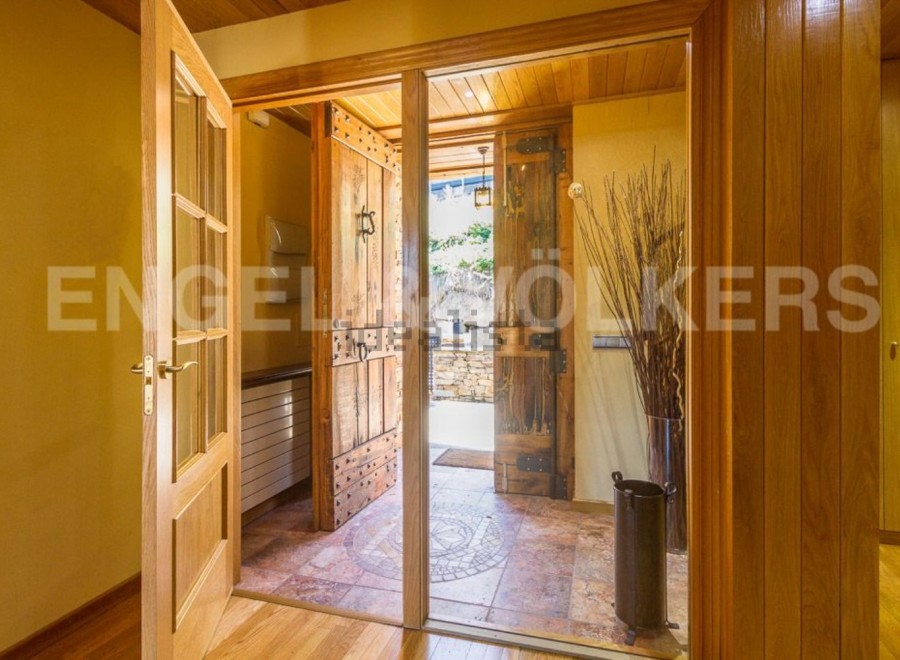 This stunning property boasts a grand entrance with rustic wooden doors, creating a warm and inviting atmosphere.