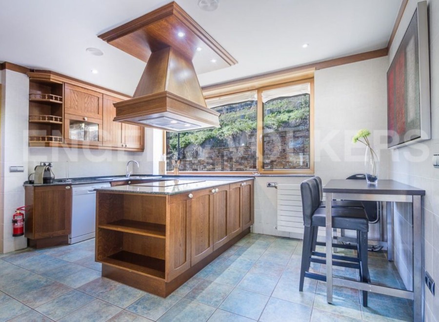 This stunning kitchen boasts a large island with granite countertops and ample wooden cabinetry, perfect for both cooking and entertaining.