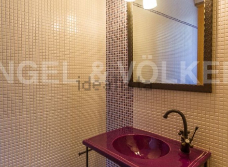 This stylish bathroom boasts a unique purple sink and dark metal stand, adding a touch of modern elegance.