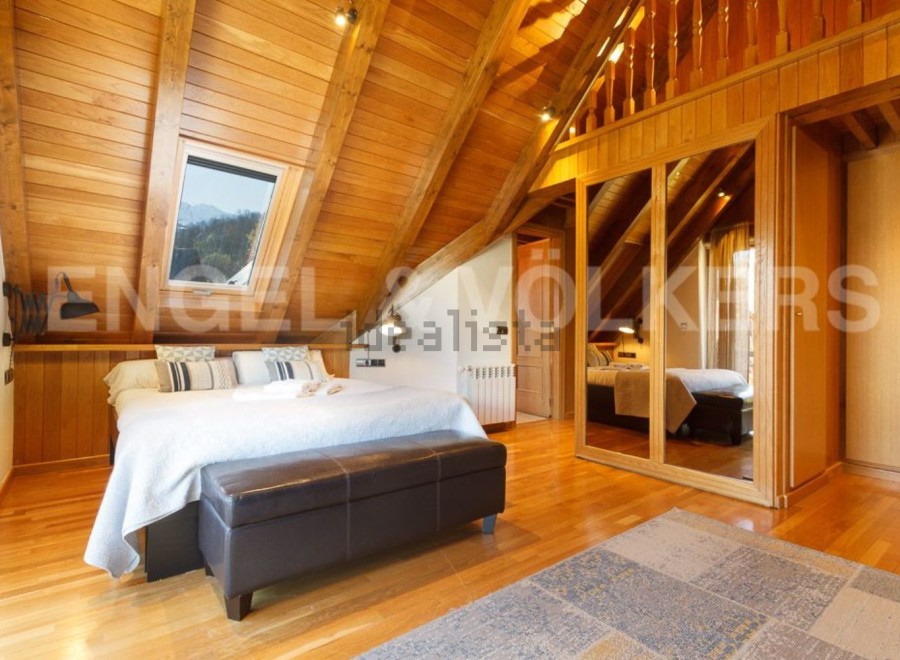 This stunning attic bedroom boasts a cozy wooden interior, complete with a comfortable bed and stylish seating.