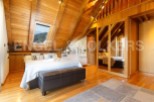 This stunning attic bedroom boasts a cozy wooden interior, complete with a comfortable bed and stylish seating.