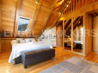This stunning attic bedroom boasts a cozy wooden interior, complete with a comfortable bed and stylish seating.