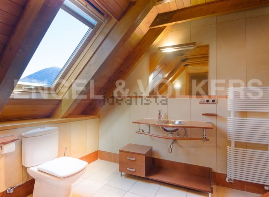 Charming attic bathroom with wooden beams, skylight, and modern fixtures.