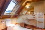 Charming attic bathroom with wooden beams, skylight, and modern fixtures.