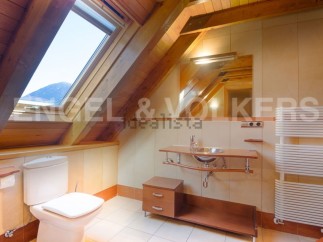 Charming attic bathroom with wooden beams, skylight, and modern fixtures.