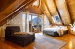This stunning attic bedroom boasts a wood-beamed ceiling, large windows offering mountain views, and a luxurious feel.