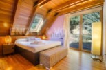 Cozy chalet bedroom with wooden beams, large windows offering scenic views, and a comfortable bed.