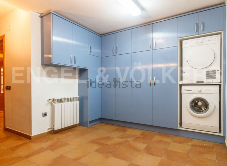 This stunning property boasts a laundry room complete with modern washer and dryer, tucked neatly into stylish blue cabinetry.