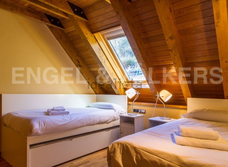 Cozy attic bedroom with wooden beams and skylights.