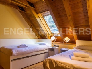 Cozy attic bedroom with wooden beams and skylights.