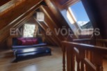 Cozy attic room with wooden beams, skylights offering mountain views, and a comfortable sofa.
