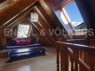 Cozy attic room with wooden beams, skylights offering mountain views, and a comfortable sofa.