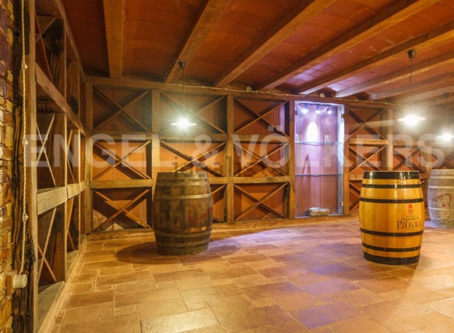 This stunning wine cellar boasts a rustic-chic design with exposed wooden beams and terracotta tile flooring.