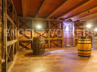 This stunning wine cellar boasts a rustic-chic design with exposed wooden beams and terracotta tile flooring.