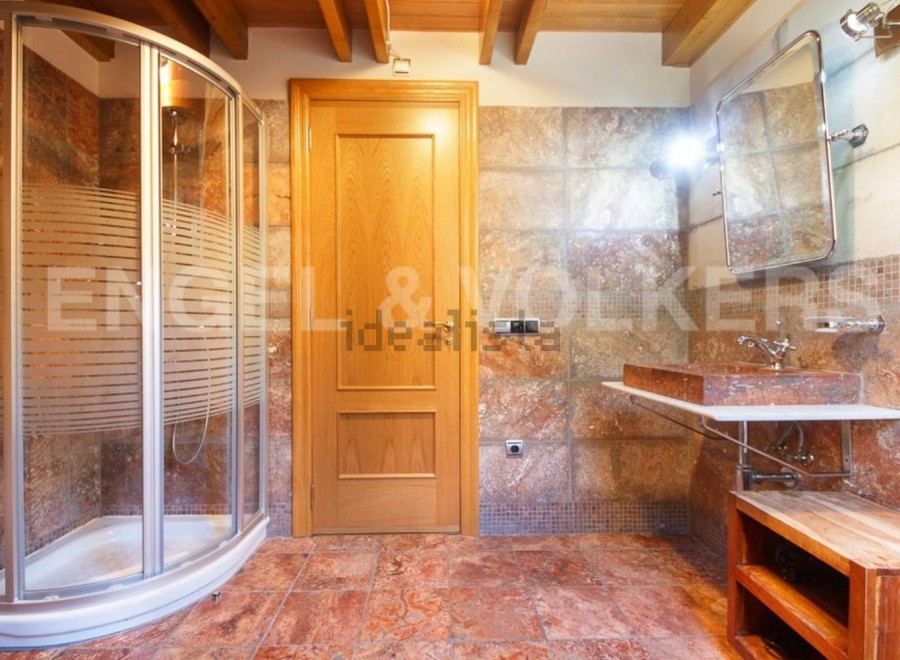 This stunning bathroom boasts a spacious shower enclosure, a sleek floating sink, and rich terracotta-toned tile flooring.