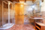 This stunning bathroom boasts a spacious shower enclosure, a sleek floating sink, and rich terracotta-toned tile flooring.