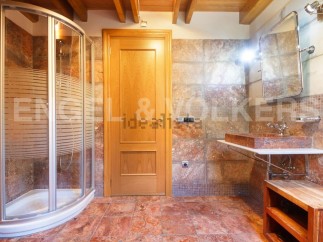 This stunning bathroom boasts a spacious shower enclosure, a sleek floating sink, and rich terracotta-toned tile flooring.