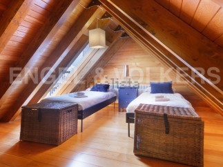 Charming attic bedroom with twin beds, wooden beams, and plenty of natural light.