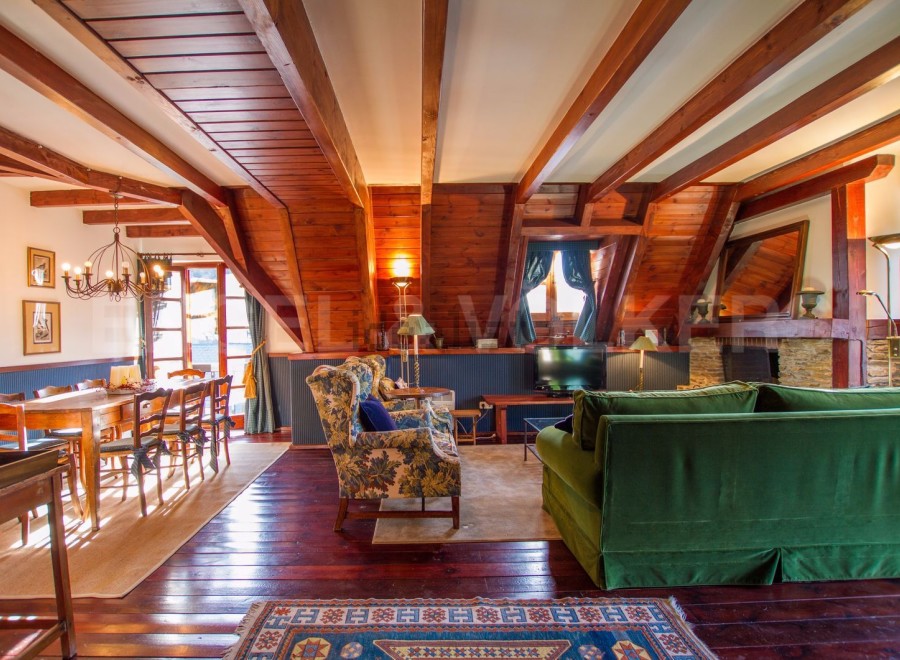 This stunning chalet boasts a spacious open-plan living area with exposed wooden beams and a cozy fireplace.