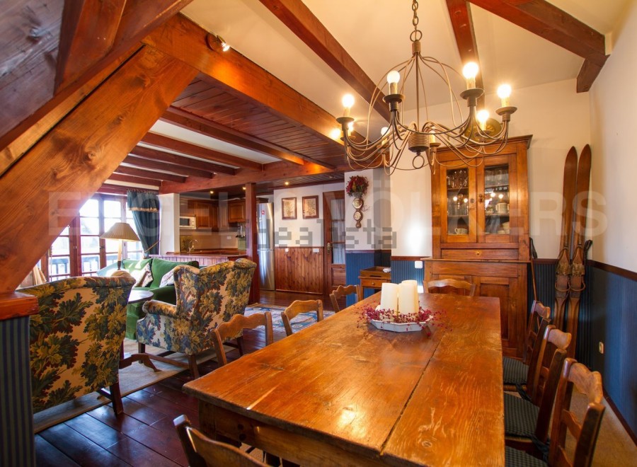 This charming chalet boasts a spacious dining area with a rustic wooden table, perfect for family gatherings.