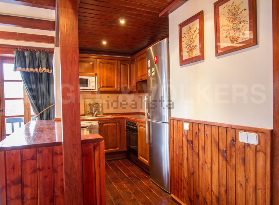 Cozy mountain chalet kitchen with wooden finishes and stainless steel appliances.