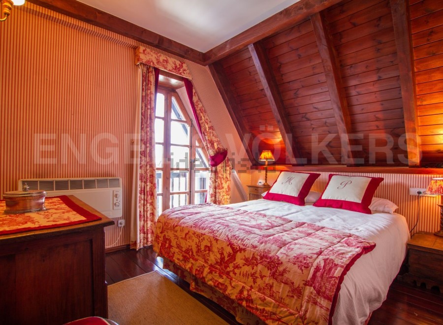 Charming attic bedroom with sloped ceilings and wood paneling.