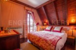 Charming attic bedroom with sloped ceilings and wood paneling.