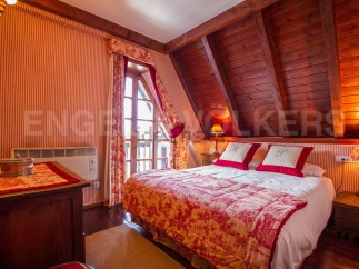 Charming attic bedroom with sloped ceilings and wood paneling.