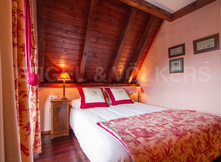 Cozy attic bedroom with wooden beams and red and white toile bedding.
