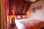Cozy attic bedroom with wooden beams and red and white toile bedding.
