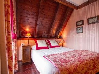 Cozy attic bedroom with wooden beams and red and white toile bedding.