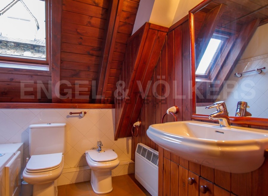 Charming attic bathroom with wooden beams and sloped ceilings.