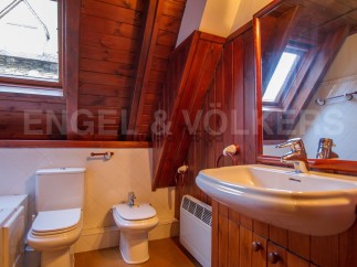 Charming attic bathroom with wooden beams and sloped ceilings.